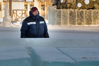 İş yerinde mavi ceketli ve örgü şapkalı bir işçinin yakın çekimi.