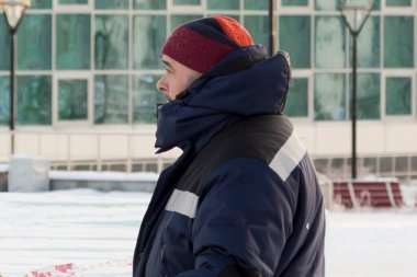 Mavi ceketli ve kırmızı örgü şapkalı bir işçi.