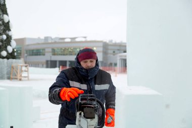 Montaj alanında elinde testere olan bir işçi.
