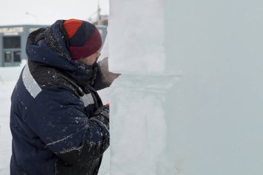 Çalışan bir montajcının portresi mavi ceketli ve buz figürünün yanında örülmüş bir şapka.