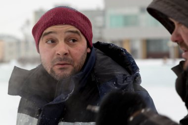 İş yerinde mavi ceketli ve örgü şapkalı bir işçinin yakın çekimi.