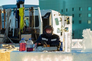 Montaj alanında elinde testere olan bir işçi.