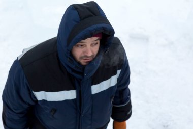 İş yerinde mavi ceketli ve örgü şapkalı bir işçinin yakın çekimi.