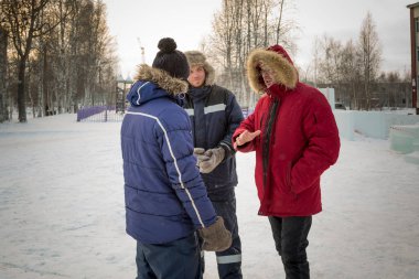 Kırmızı ceketli bir lider inşaat alanında astlarıyla konuşuyor.