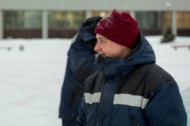 İş yerinde mavi ceketli ve örgü şapkalı bir işçinin yakın çekimi.