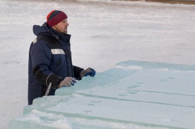 Mavi ceketli ve kırmızı örgü şapkalı bir işçi.