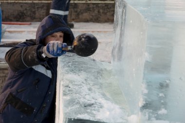 Bir işçi buz tabakasına bir kepçe su döker.