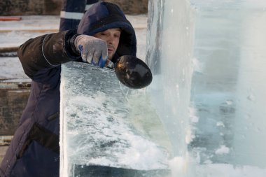 Bir işçi buz tabakasına bir kepçe su döker.