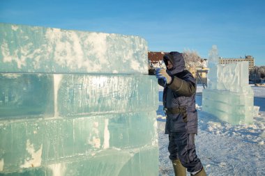 Kışlık ceketli bir montajcının portresi ve buz tahtına örülmüş siyah bir şapka.