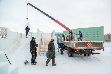 İşçiler ahşap kaydırağın çerçevesini buz panelleriyle kaplıyorlar.