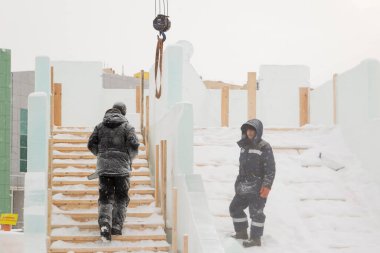 İşçi buz şehrin montaj yerinde elinde testere ile