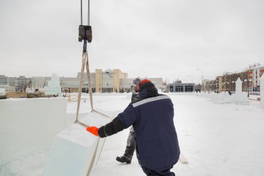 İki toplayıcı işçi, buz kasabasının inşaat sahasında buz tabakaları depoluyorlar.