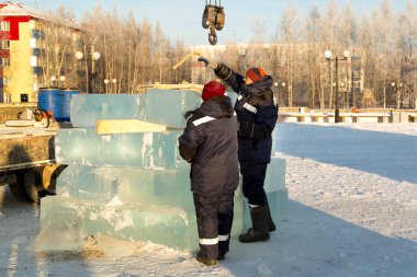 İnşaat alanına buz döşeyen iki montaj işçisi.