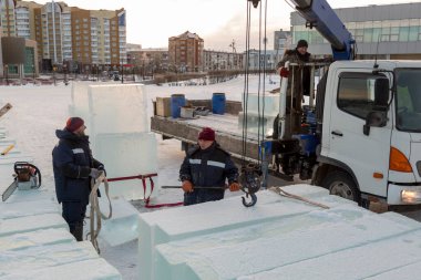 İnşaat alanına buz döşeyen iki montaj işçisi.