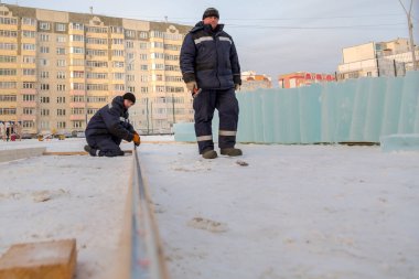 İşçi derleyici bir mezura ile tahtayı işaretler