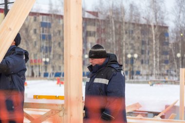 İşçiler ahşap bir kaydırağın ahşap kirişini düzleştiriyorlar.