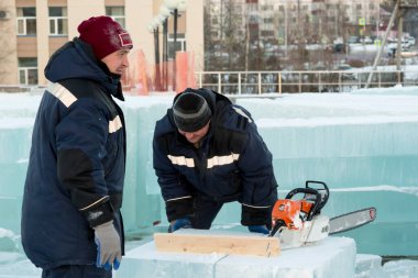 İşçiler, buz kasabasının bölgesindeki buz bloğunu bir yönetim kurulunun yardımıyla işaretliyor.