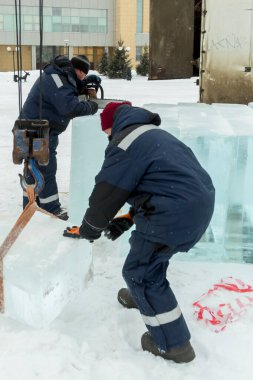 Mavi ceketli Slinger derleyicisi buz panellerini kamyon vinçiyle boşaltıyor.