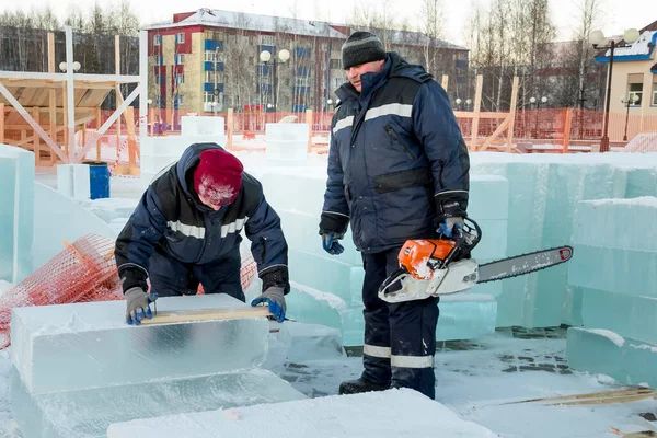 Workers installers mark the ice block on the territory of the ice town with the help of a board