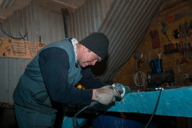 Öğütücü kullanan bir işçi metal bir parçayı işliyor.