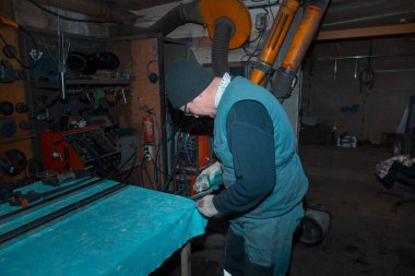 Öğütücü kullanan bir işçi metal bir parçayı işliyor.