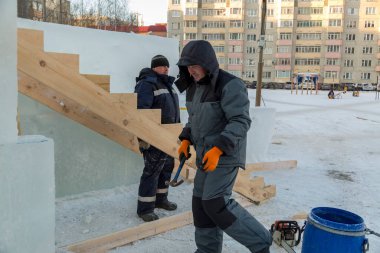 İki işçi ahşap kirişlerden kayan iskeleti birleştiriyor.
