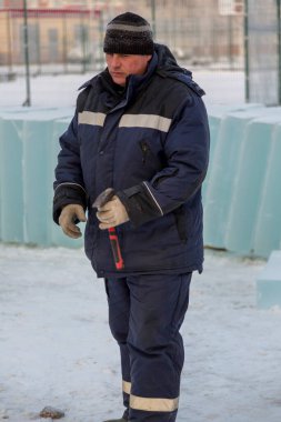 İş yerinde kapüşonlu ve yün örgü şapkalı bir işçi.