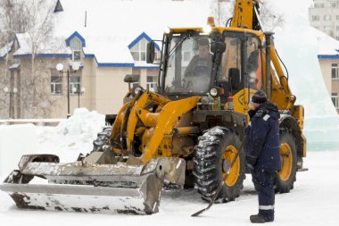 İnşaat işçisi buz kasabasından kar temizliyor.