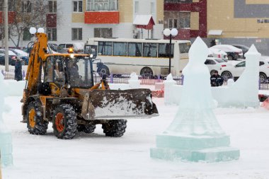 İnşaat işçisi buz kasabasından kar temizliyor.