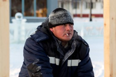 İş yerinde kapüşonlu ve yün örgü şapkalı bir işçi.