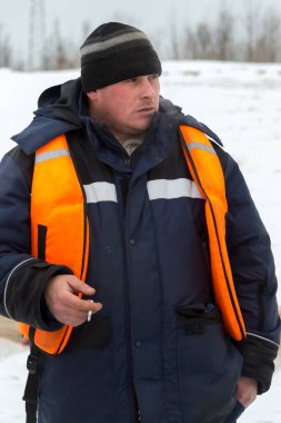 İş yerinde kapüşonlu ve yün örgü şapkalı bir işçi.