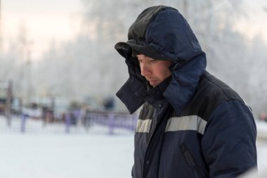Buz kasabasının inşaat alanında mavi kapüşonlu ceketli bir işçinin portresi.