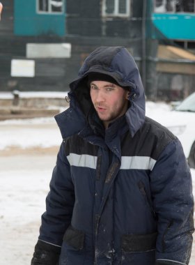 İnşaat alanında, kafasında başlığı olan mavi ceketli bir işçinin portresi.