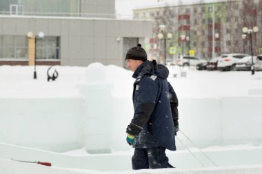 Buz kasabasının inşaat alanında mavi kapüşonlu ceketli bir işçinin portresi.