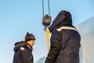 Kapüşonlu mavi ceketli bir işçinin portresi.