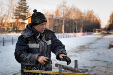 Ellerinde fırça, keski ve mertebeyle bir şantiyede tesisatçı.