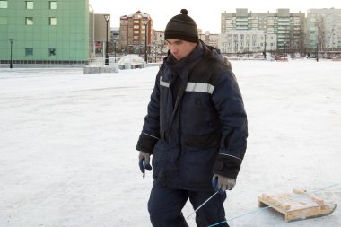 Buz kasabasının inşaat alanında mavi kapüşonlu ceketli bir işçinin portresi.