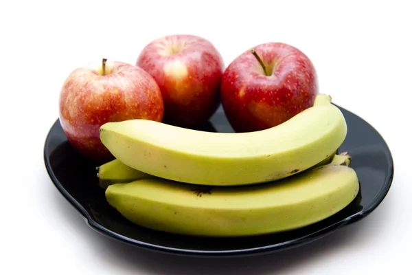 Красное яблоко с бананом на тарелке — стоковое фото