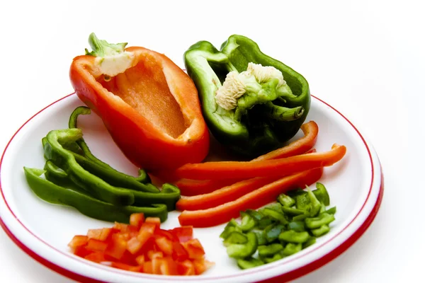 Roter und grüner Paprika in Stücken und Streifen auf Teller — Stockfoto
