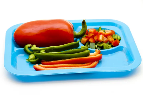 Green and red pepper in pieces and stripes on plate — Stock Photo, Image