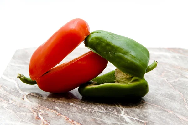 Rood en groen paprika op rand bord Stockfoto