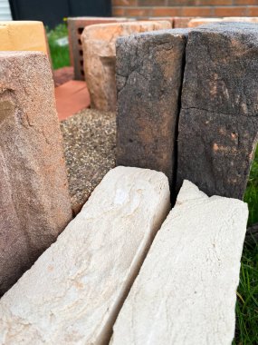 Farklı tipte tuğlalar güzel bir şekilde yeşil çimlerin üzerine istiflenmiş.