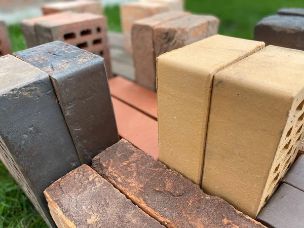 Diferentes tipos de tijolos empilhados lindamente na grama verde — Fotografia de Stock