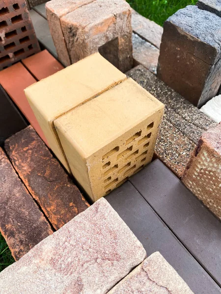 Diferentes tipos de tijolos empilhados lindamente na grama verde — Fotografia de Stock