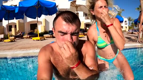 Man and woman dives into the pool on the background of the hotel. Slow motion HD video — Stock Video