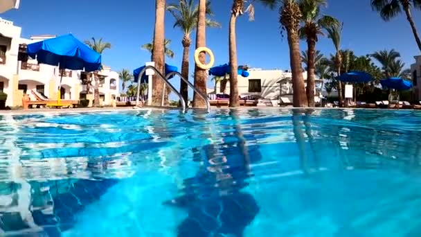 Vídeo en cámara lenta del rodaje bajo el agua en una piscina con un buceo fuera del agua y una vista del hotel — Vídeos de Stock