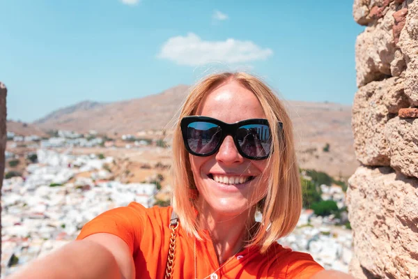 En blond kvinna tittar på panorama över Lindos på ön Rhodos, Grekland — Stockfoto