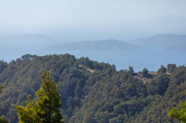 Çok katmanlı arka planlara sahip deniz manzarası mesafeye doğru çekiliyor. Denizde dağların siluetleri