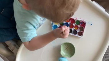 Küçük çocuk Paskalya için annesiyle yumurta boyuyor.