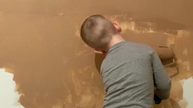 Küçük bir çocuk terracotta 'daki odasında silindirli bir duvar boyuyor.